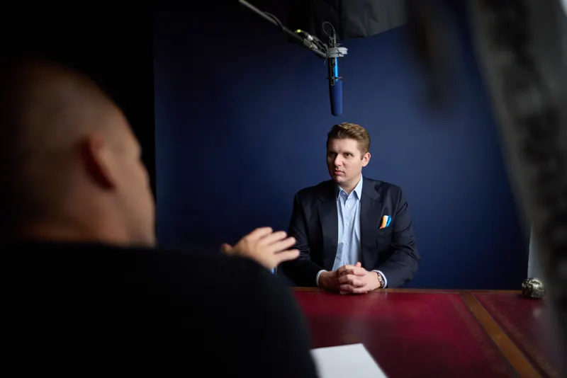 Interview vor dunkelblauem Hintergrund mit Richtmikrofon über dem Tisch