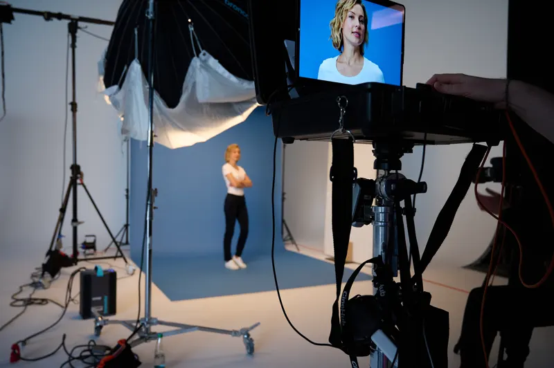 Kontrollmonitor mit Livebild, im Hintergrund steht das Model vor blauem Grund