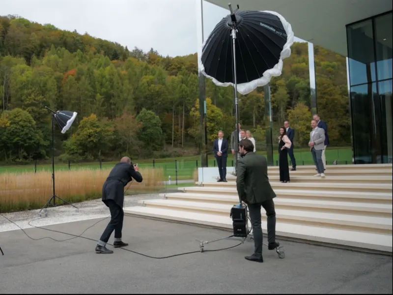 Fotograf fotografiert eine Gruppe auf einer Treppe, zwei große Lichtschirme stehen bereit