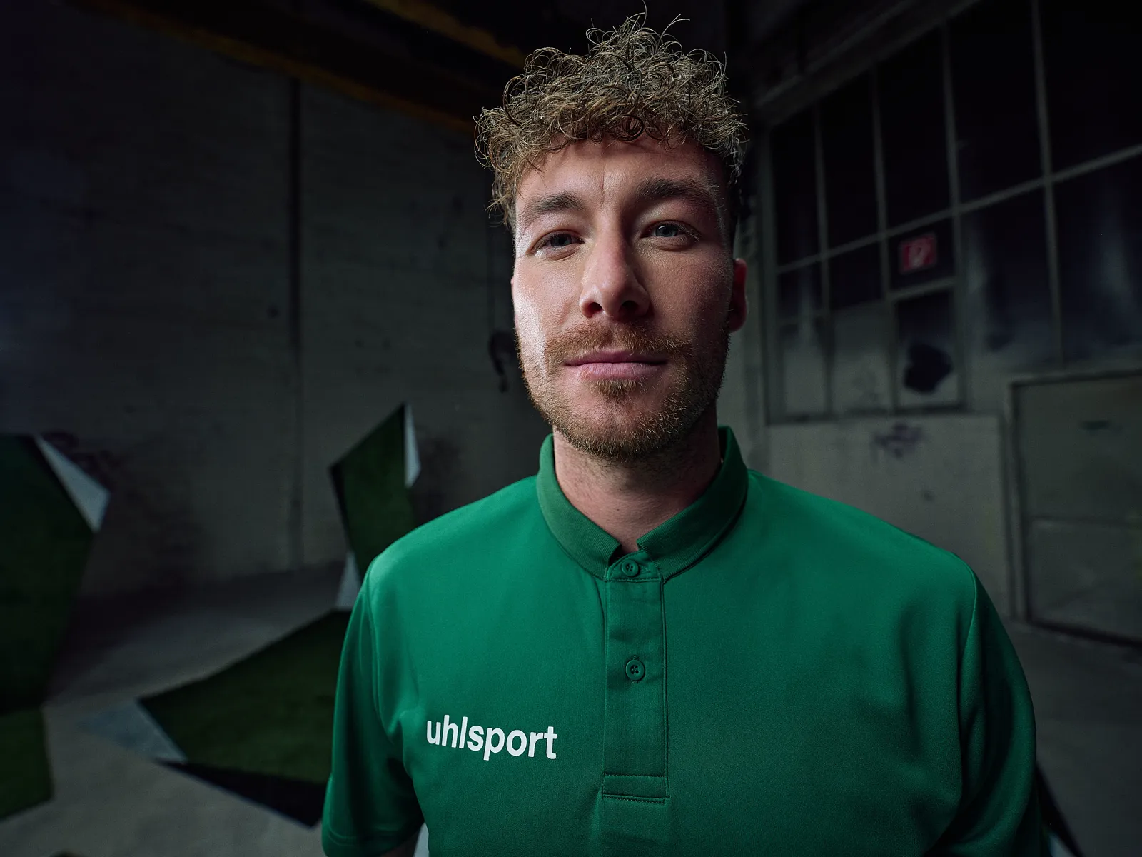 Spieler im grünen Poloshirt, Porträt in der dunklen Halle