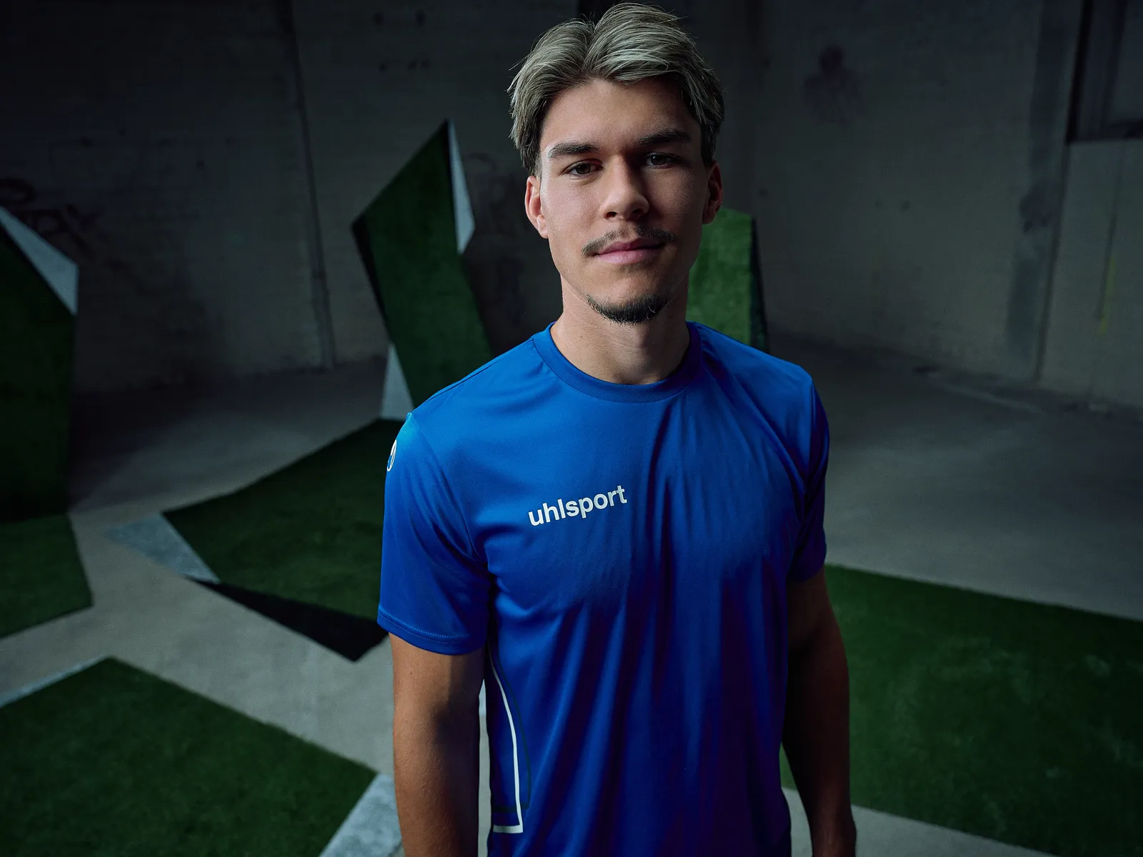 Spieler im blauen Poly-Shirt, Porträt in der dunklen Halle